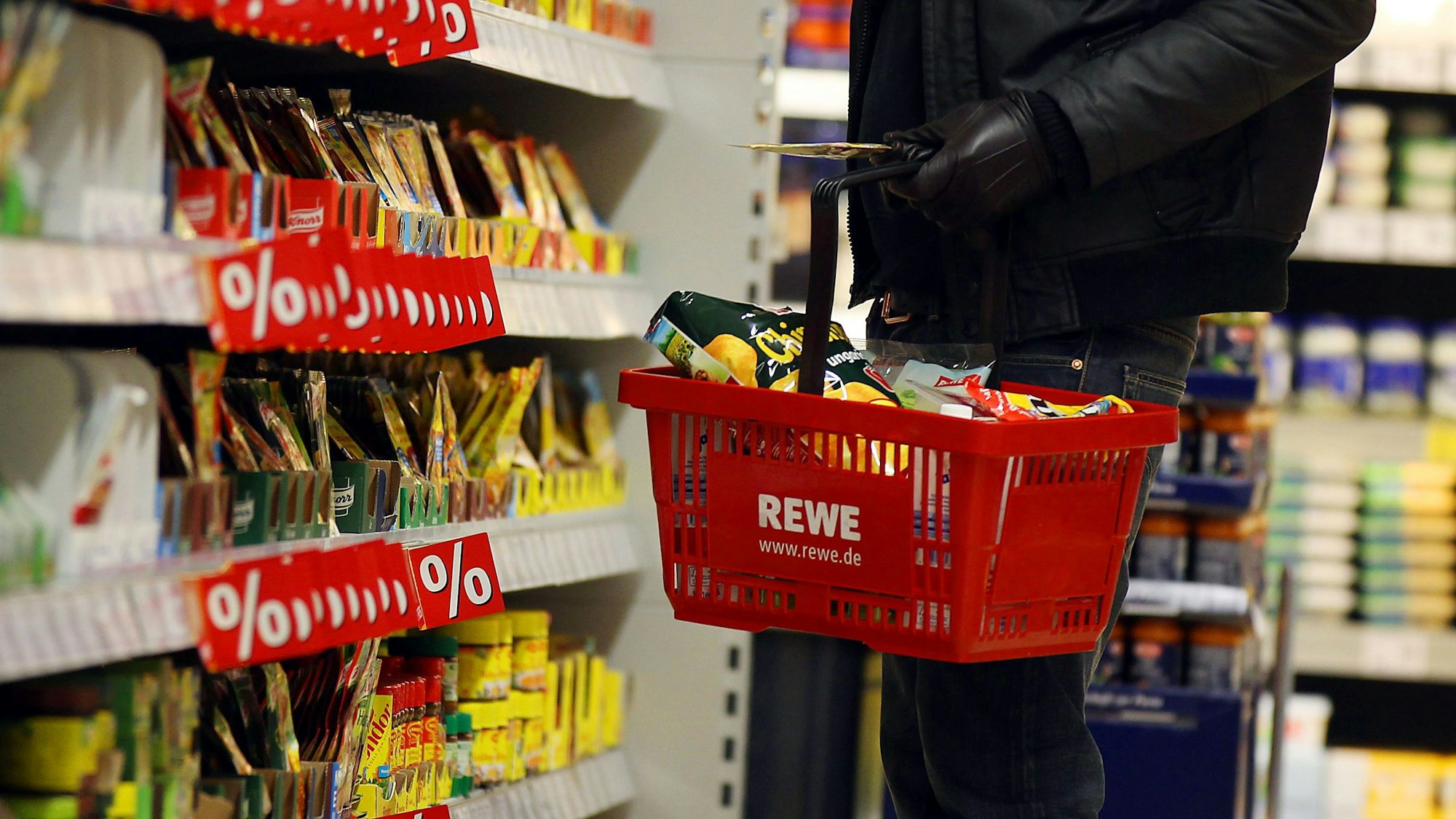 Ein Kunde steht in einem Rewe-Supermarkt.