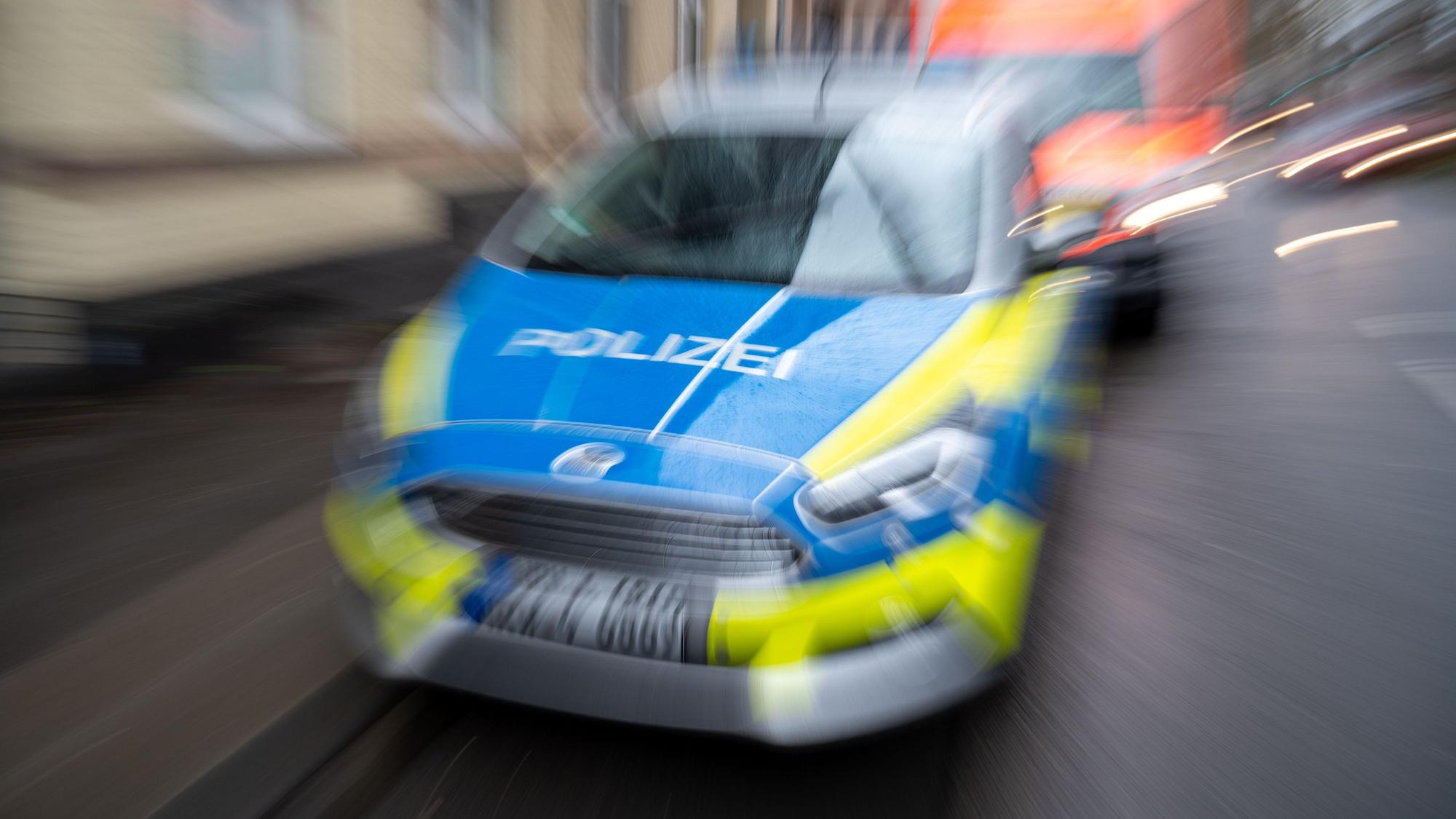 Ein Einsatzfahrzeug der Kölner Polizei fährt auf der Straße, dahinter ist ein Krankenwagen zu sehen.