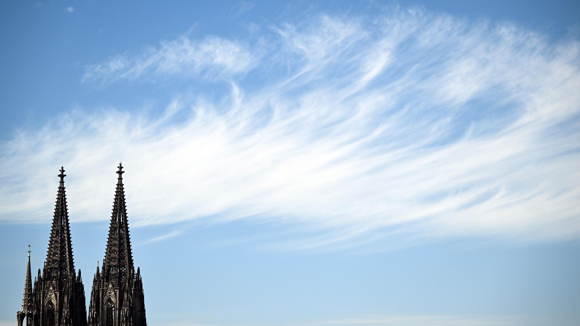 24.08.2022, Nordrhein-Westfalen, Köln: Ein Wolke zieht hinter den Türmen des Doms vorbei. In Nordrhein-Westfalen ist in den kommenden Tagen viel Sonne angesagt. Die Temperaturen werden mit 30 bis 34 Grad erwartet. Foto: Federico Gambarini/dpa +++ dpa-Bildfunk +++
