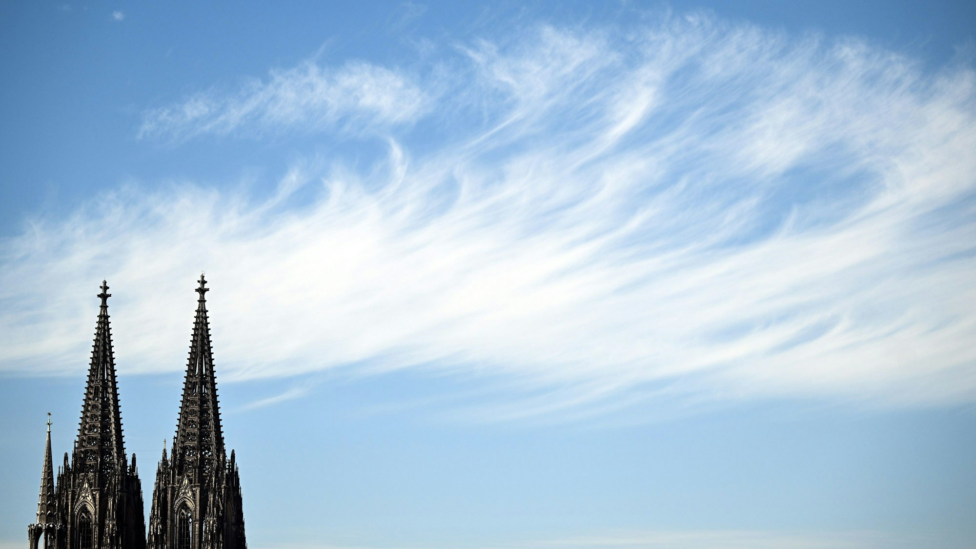 24.08.2022, Nordrhein-Westfalen, Köln: Ein Wolke zieht hinter den Türmen des Doms vorbei. In Nordrhein-Westfalen ist in den kommenden Tagen viel Sonne angesagt. Die Temperaturen werden mit 30 bis 34 Grad erwartet. Foto: Federico Gambarini/dpa +++ dpa-Bildfunk +++