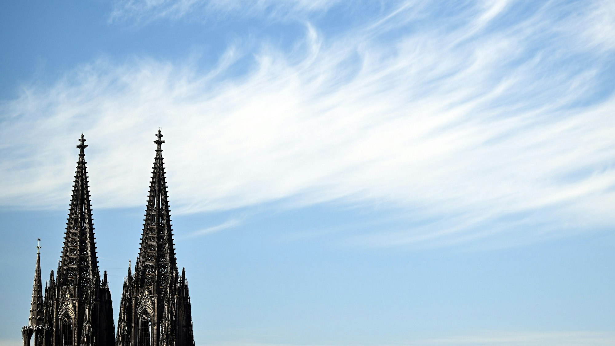 Eine Wolke zieht hinter den Türmen des Kölner Doms vorbei.