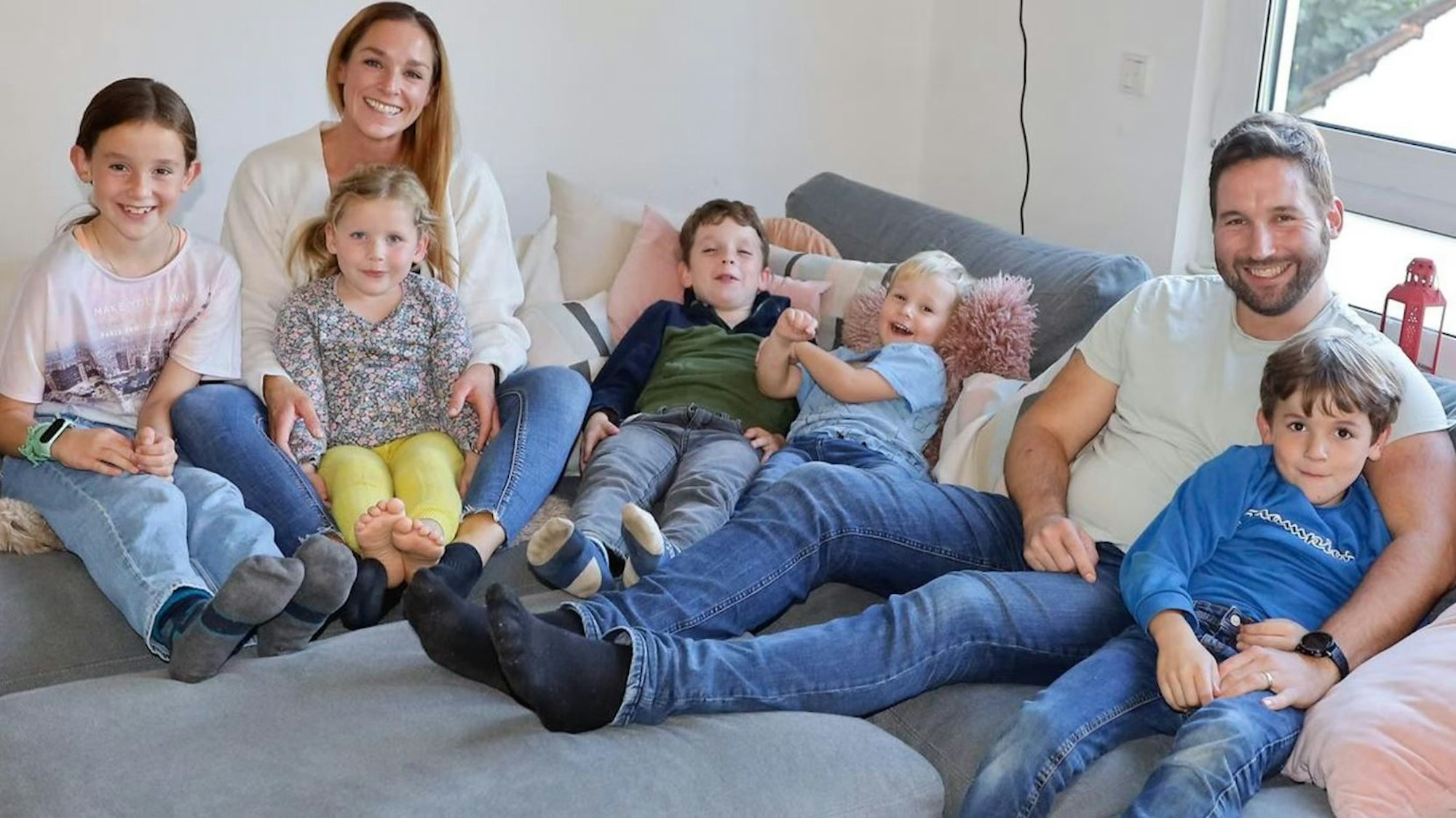 Porträt einer Großfamilie: Eltern und fünf Kinder auf einem Sofa