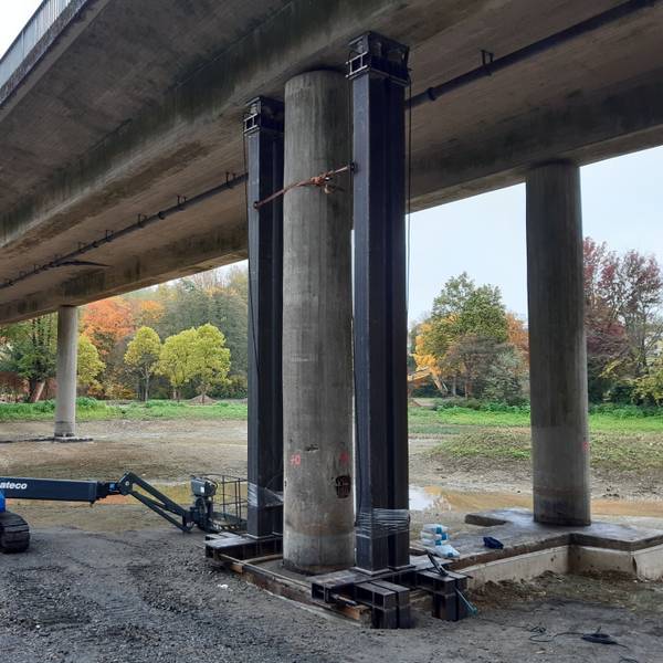 Eine Autobrücke mit Betonpfeilern ist von unten zusehen.