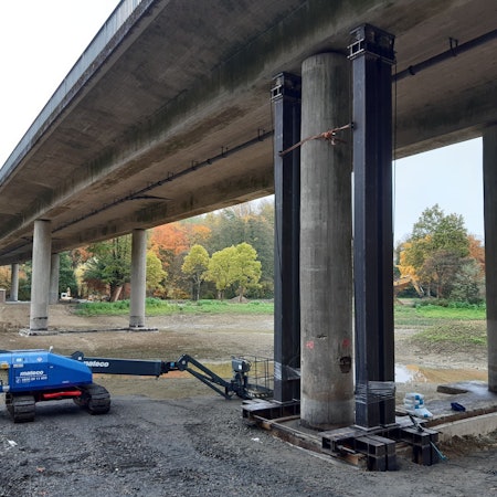 Eine Autobrücke mit Betonpfeilern ist von unten zusehen.