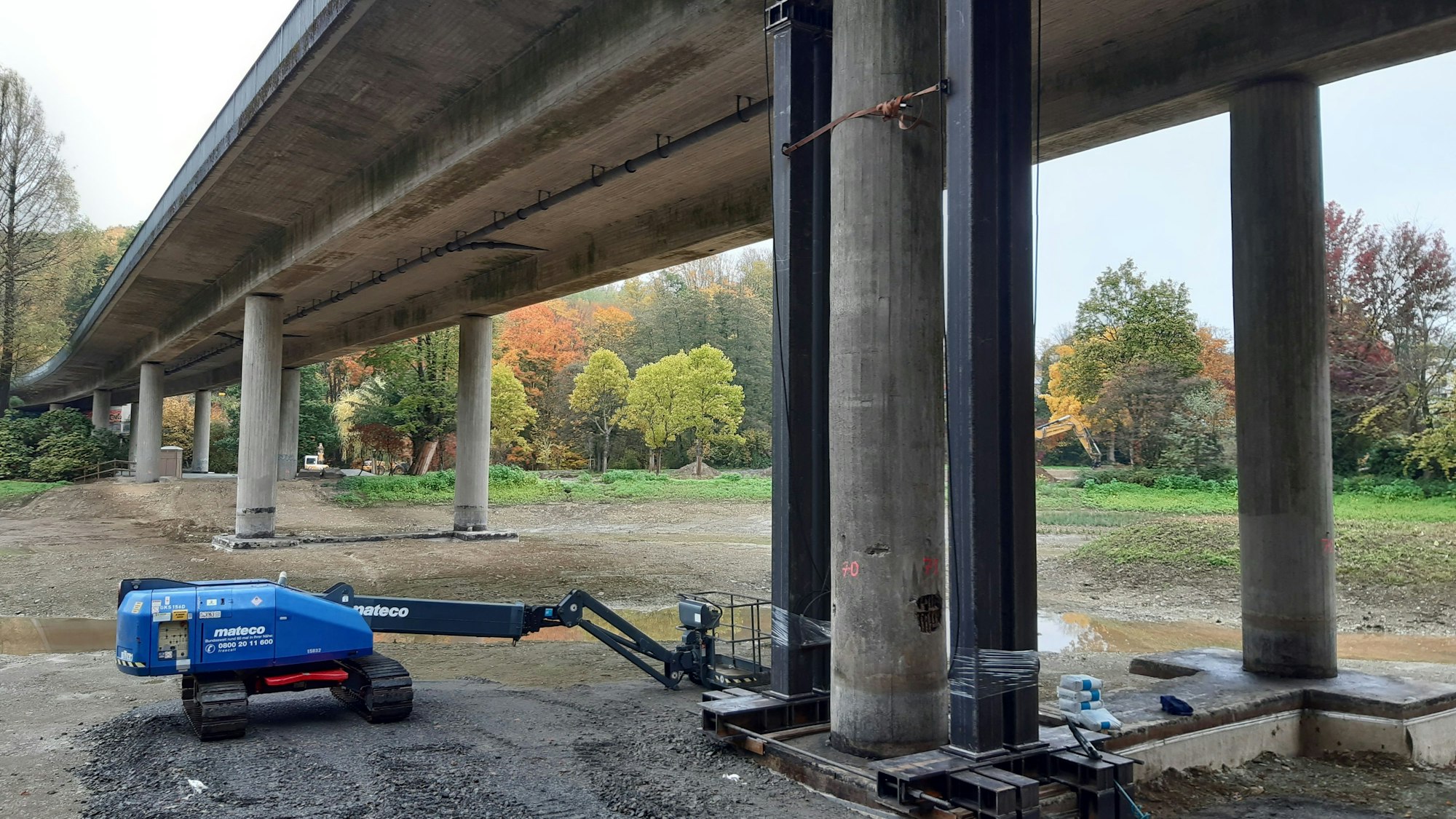 Eine Autobrücke mit Betonpfeilern ist von unten zusehen.