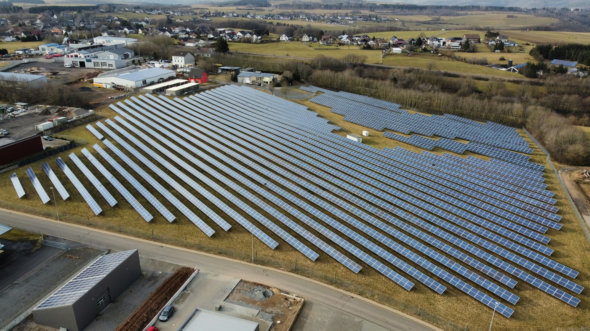 Das Bild zeigt zahlreiche lange Reihen mit Solarpanelen, die auf einer Wiese aufgetsellt sind.