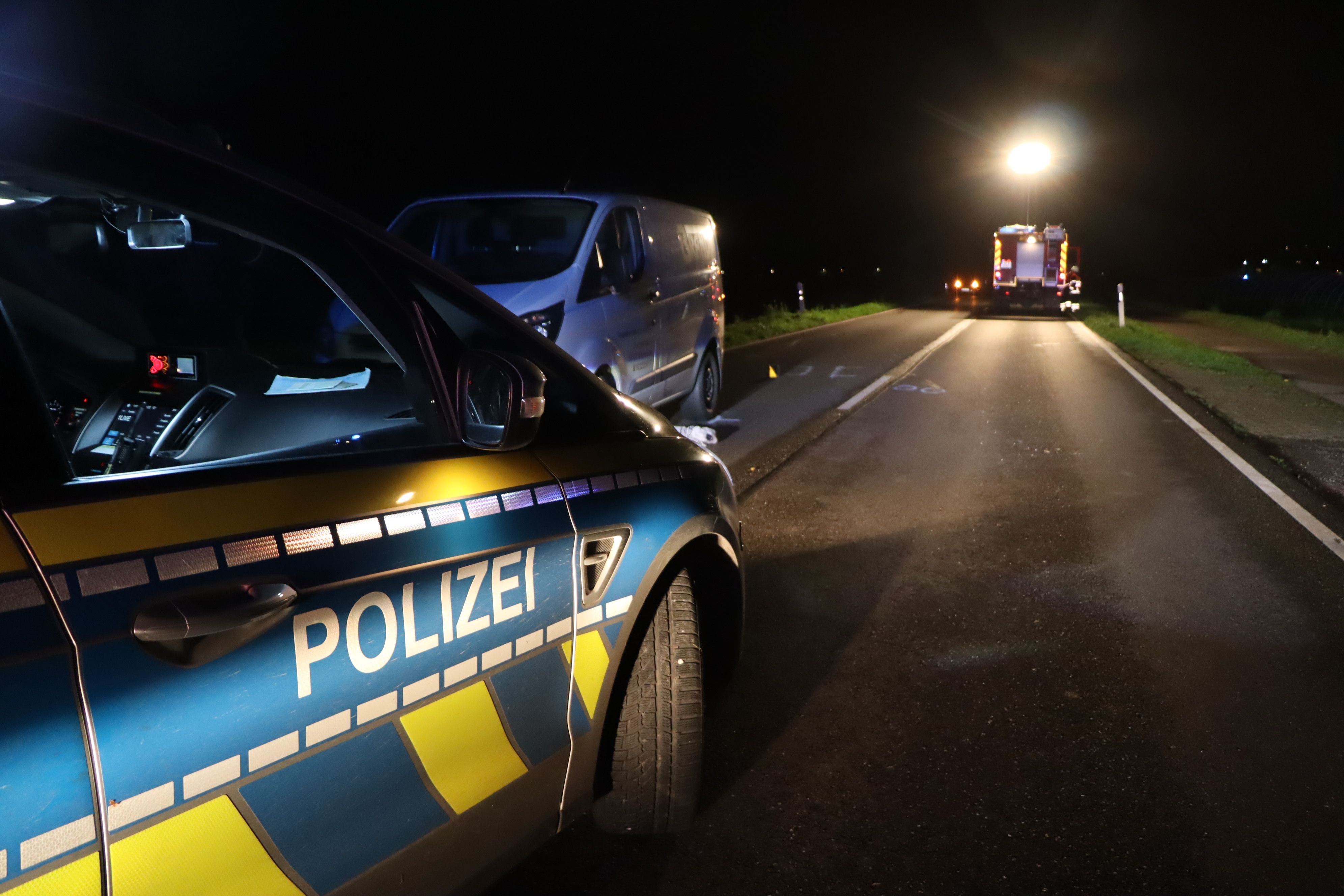 Ein Polizeiauto steht auf der Straße vor einem Transporter. Die Feuerwehr leuchtet die Unfallstelle aus.