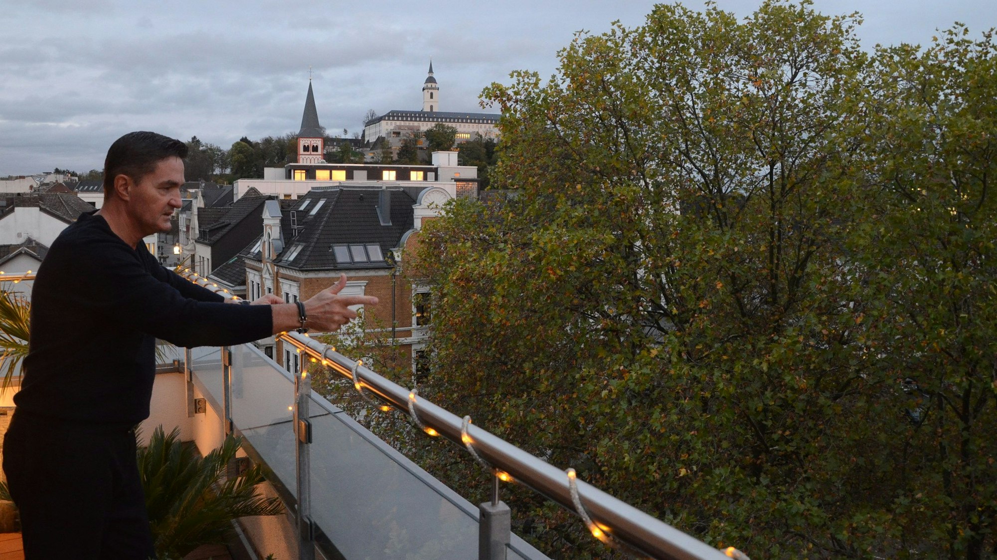 Jaroslaw Plichta blickt von seiner Wohnung im Dachgeschoss auf Bäume. Im Hintergrund sind Gebäude in Siegburg zu sehen.