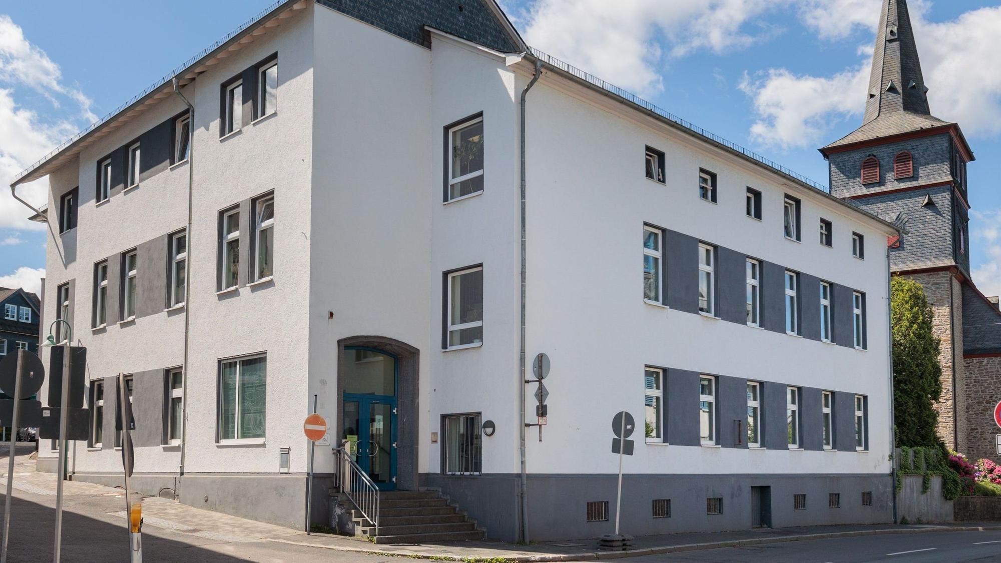 Zu sehen ist das Amtsgericht in Waldbröl, ein zweieinhalb geschossiges Gebäude, dahinter die Kirche.
