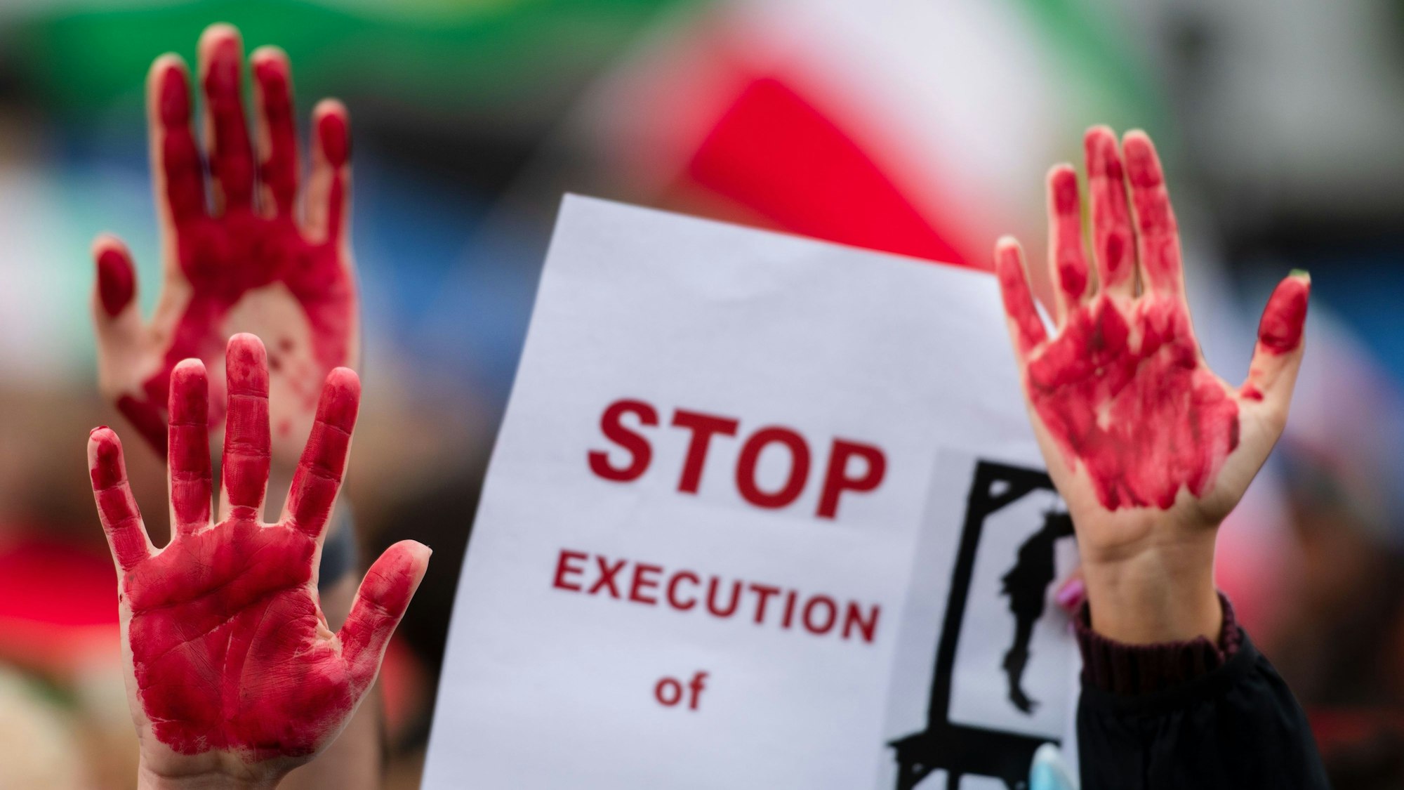 Menschen nehmen am „Marsch für die Freiheit“ teil und haben sich die Hände rot angemalt. Auf einem Plakat wird das Ende von Hinrichtungen gefordert.