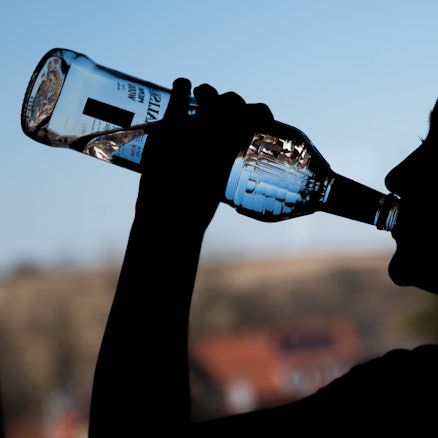 Ein Mädchen trinkt an einer Flasche Wodka.