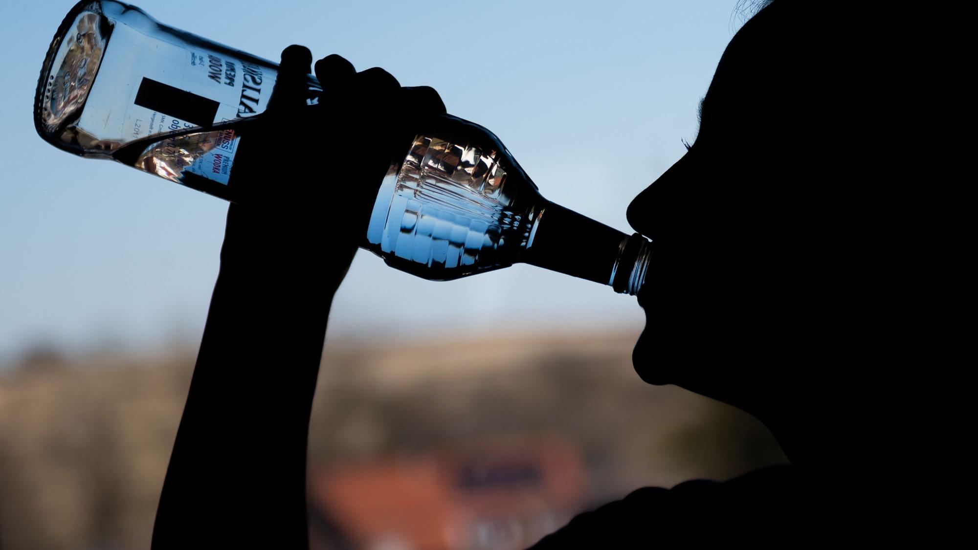 Ein Mädchen trinkt an einer Flasche Wodka.