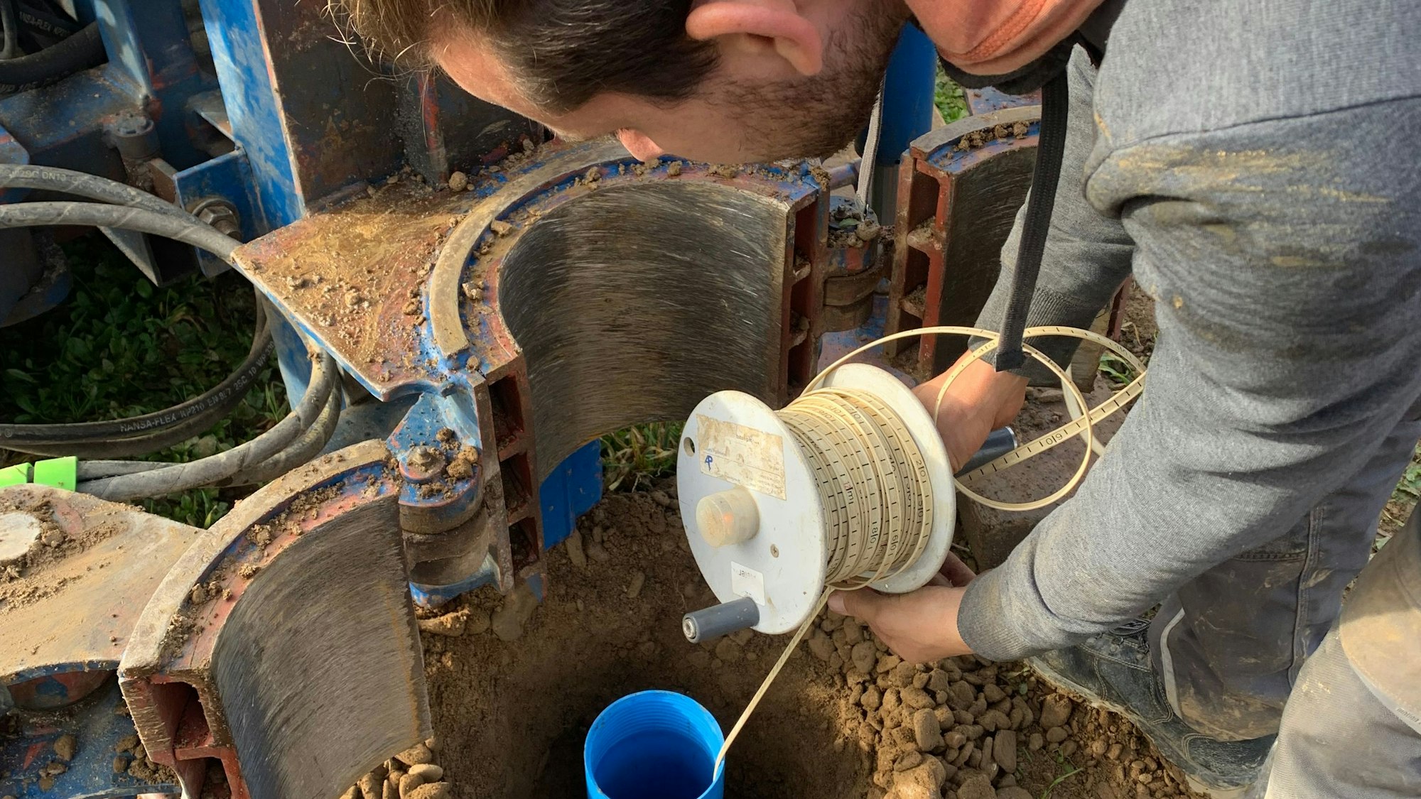 Brunnenbauer Martin Kiefer führt in Sankt Augustin ein PVC-Rohr in das Brunnenloch ein.