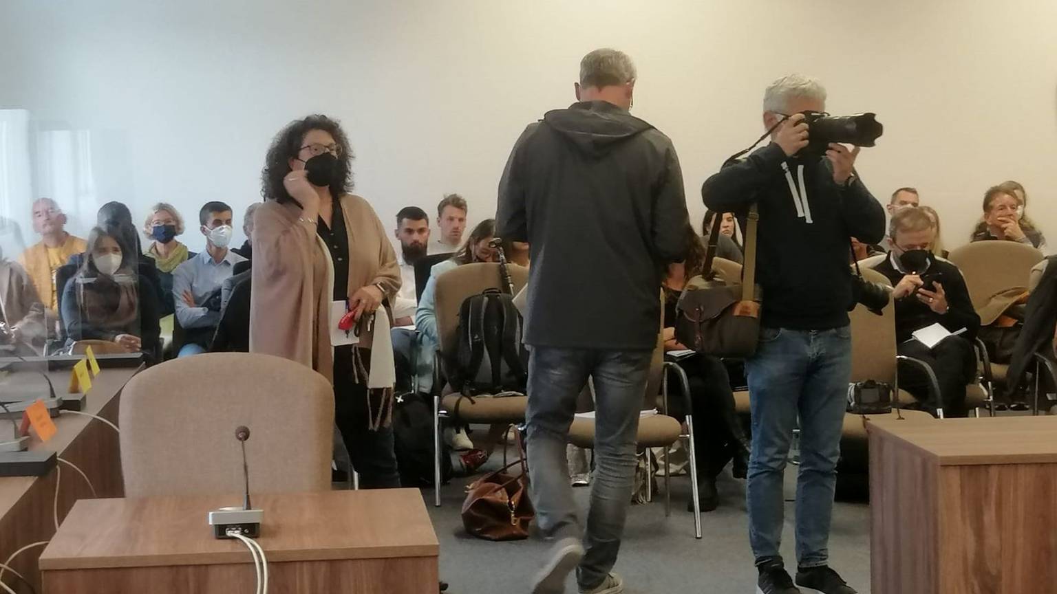 In dem Gerichtssaal sitzen viele Pressevertreter und Zuschauer.