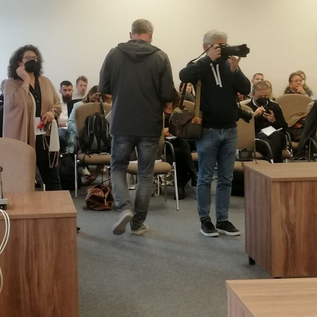 In dem Gerichtssaal sitzen viele Pressevertreter und Zuschauer.