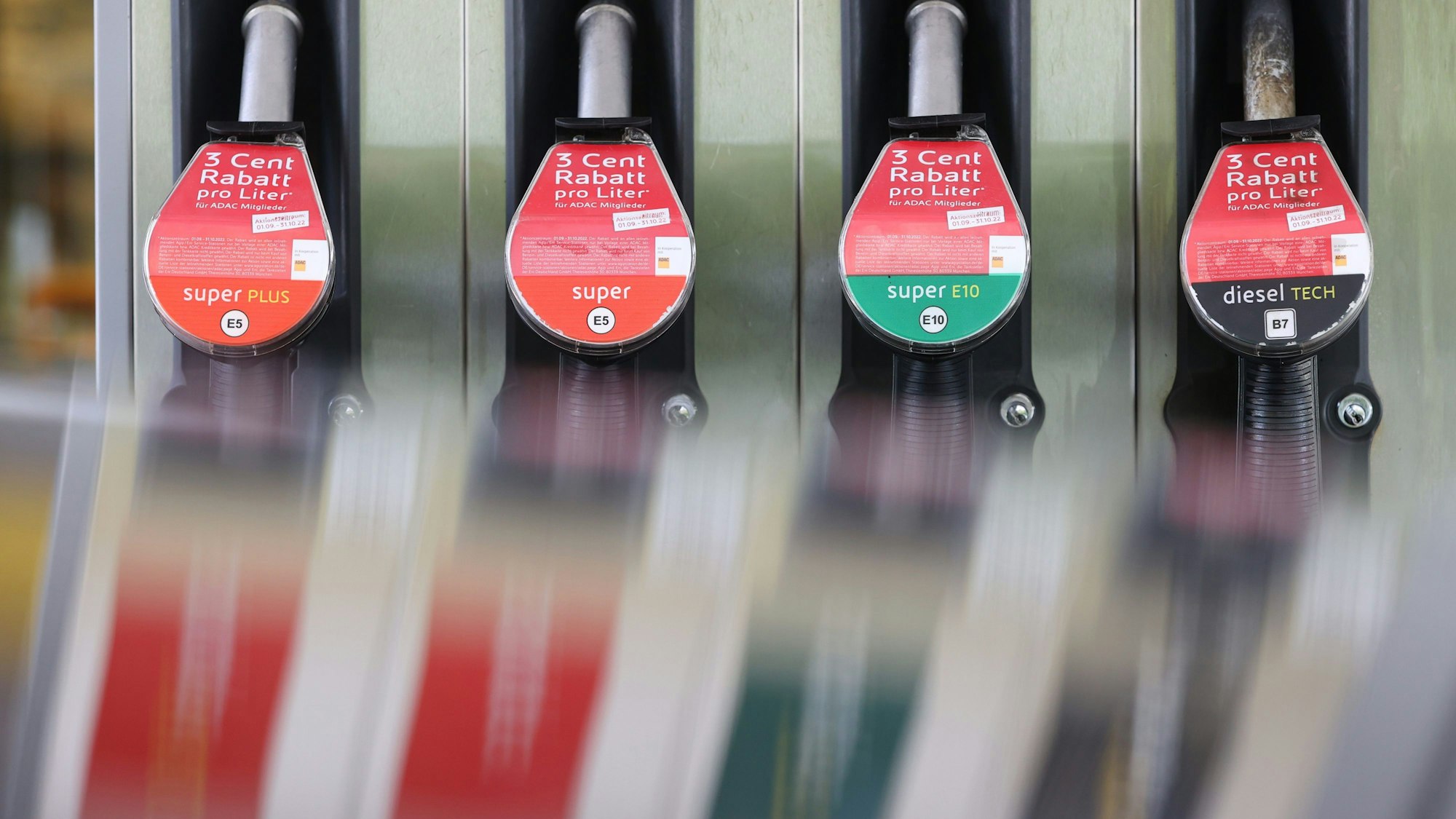 Eine Zapfsäule spiegelt sich an einer Tankstelle in einem Autodach.