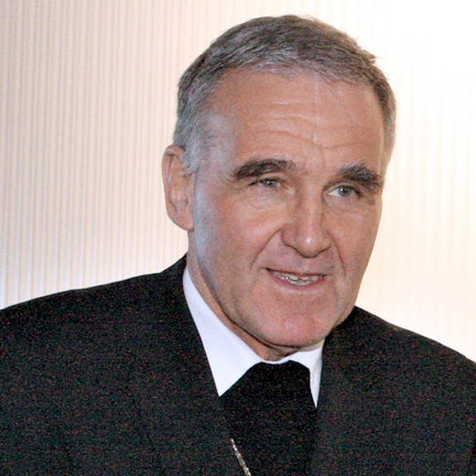 Weihbischof Johannes Bündgens vor weißem Hintergrund. Er guckt an der Kamera vorbei und lächelt leicht.