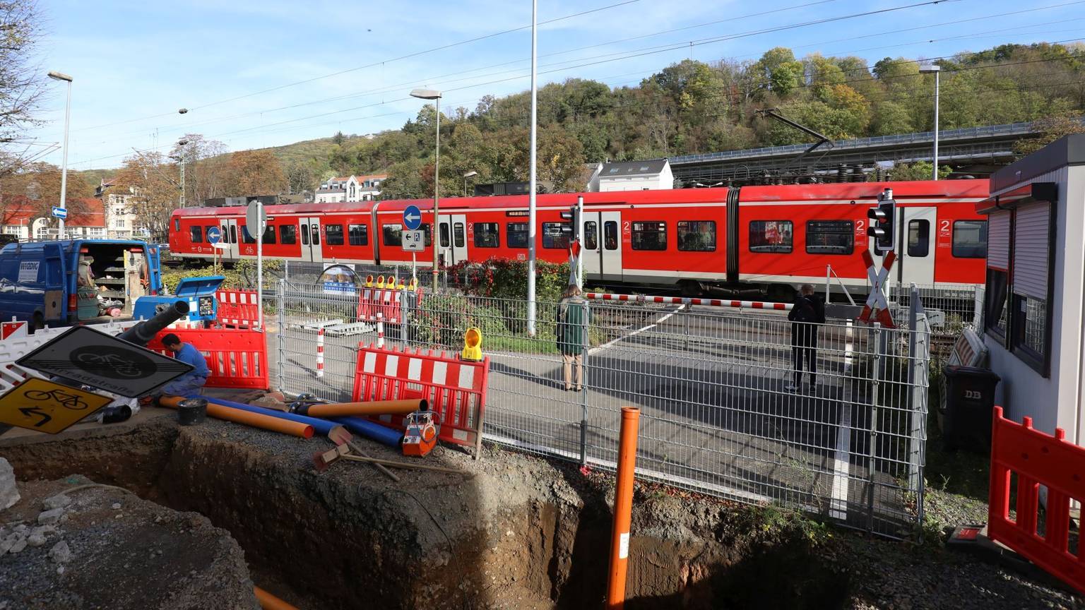 Ein Regionalzug passiert die geschlossenen Schranken am Bahnübergang Drachenfelsstraße, vor dem sich zurzeit eine Baustelle befindet.