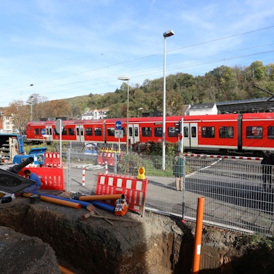 Ein Regionalzug passiert die geschlossenen Schranken am Bahnübergang Drachenfelsstraße, vor dem sich zurzeit eine Baustelle befindet.