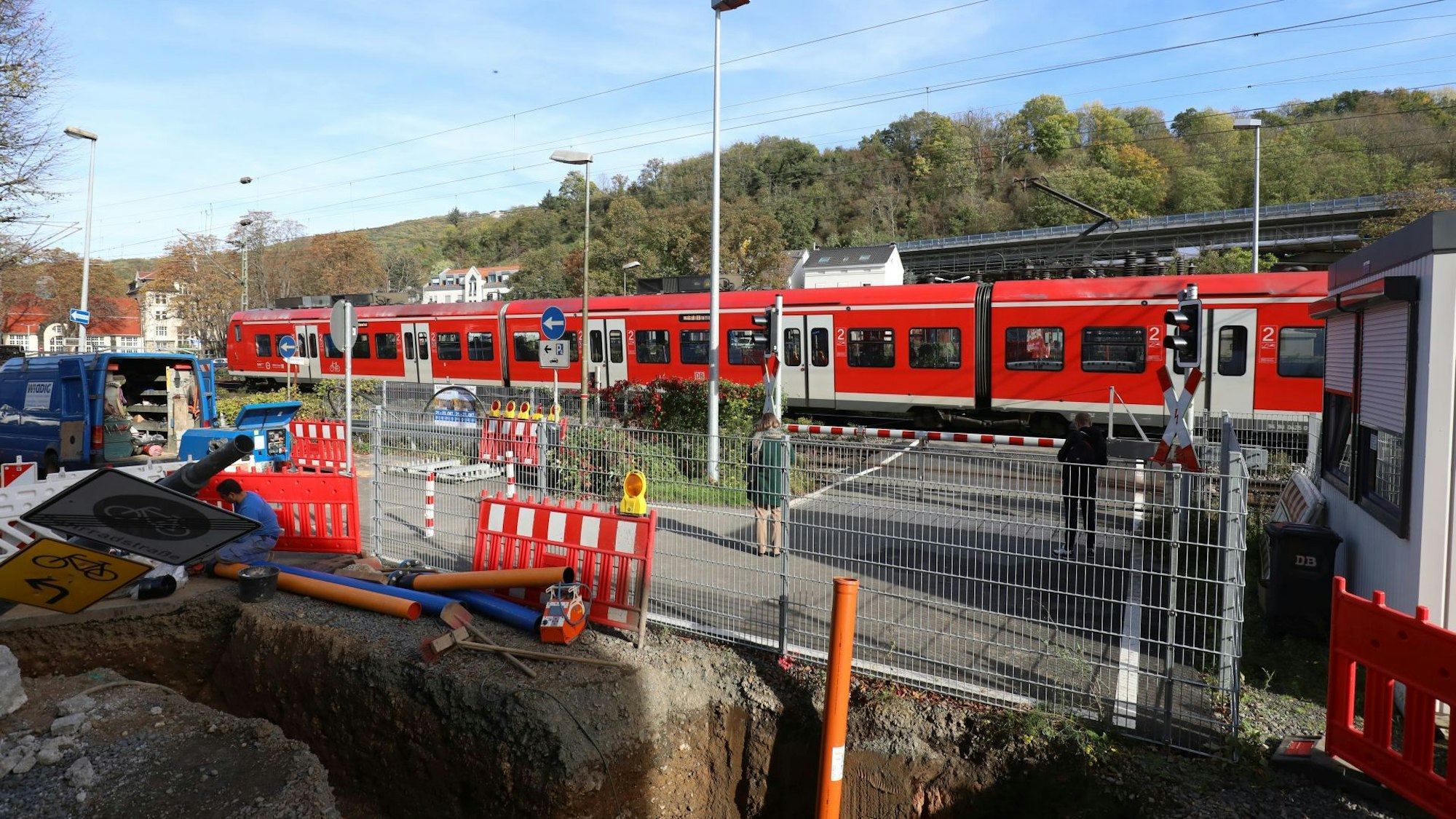 Ein Regionalzug passiert die geschlossenen Schranken am Bahnübergang Drachenfelsstraße, vor dem sich zurzeit eine Baustelle befindet.