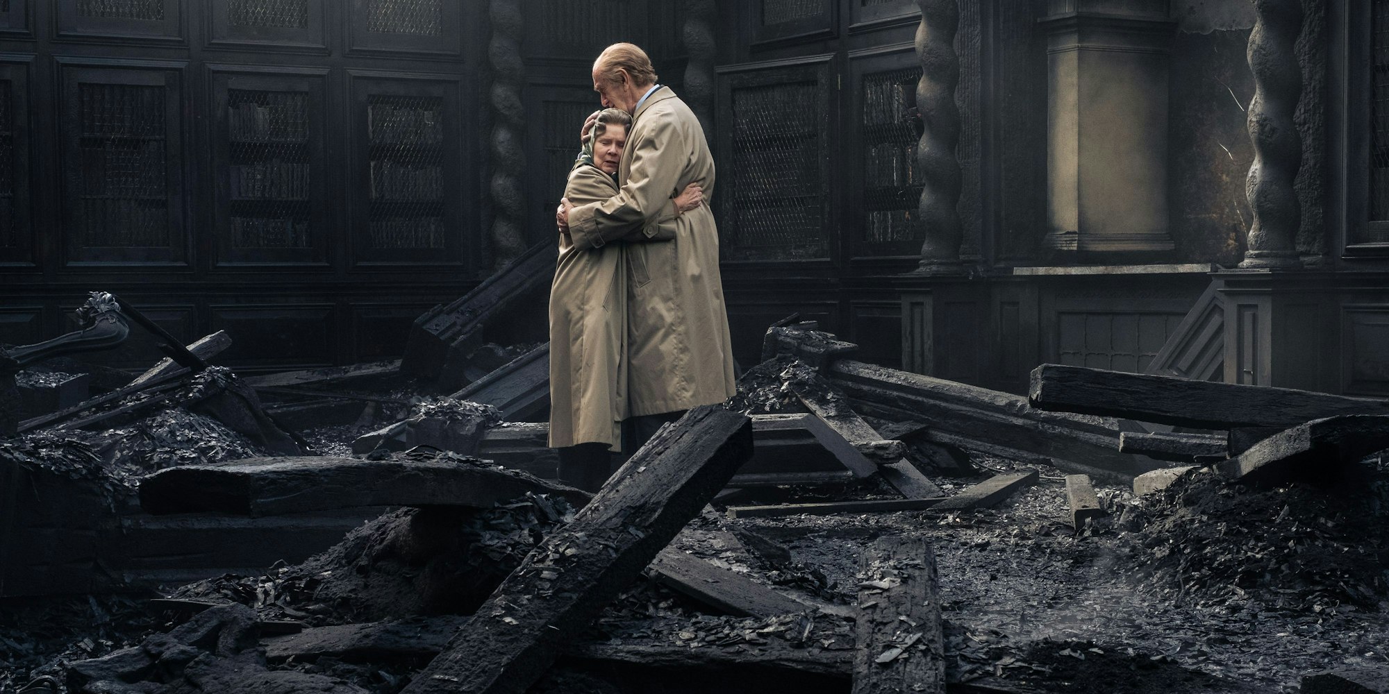 Netflix' „The Crown“-Darsteller Imelda Staunton und Jonathan Pryce umarmen sich in einem verkohlt aussehendem Raum.