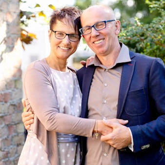 Bauer Theo steht mit seiner Freundin Andrea vor einer Hecke. Die beiden halten ihre Hände und lächeln in die Kamera.