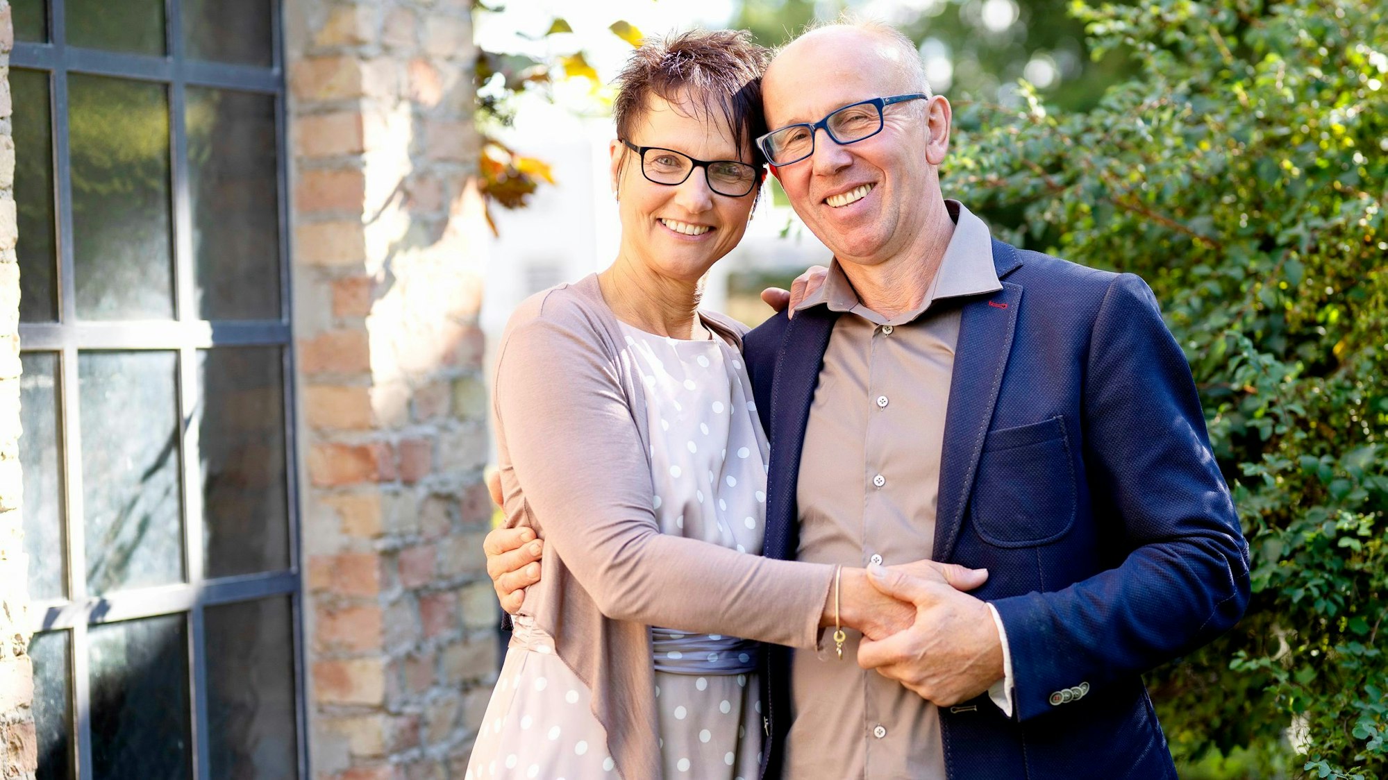 Bauer Theo steht mit seiner Freundin Andrea vor einer Hecke. Die beiden halten ihre Hände und lächeln in die Kamera.