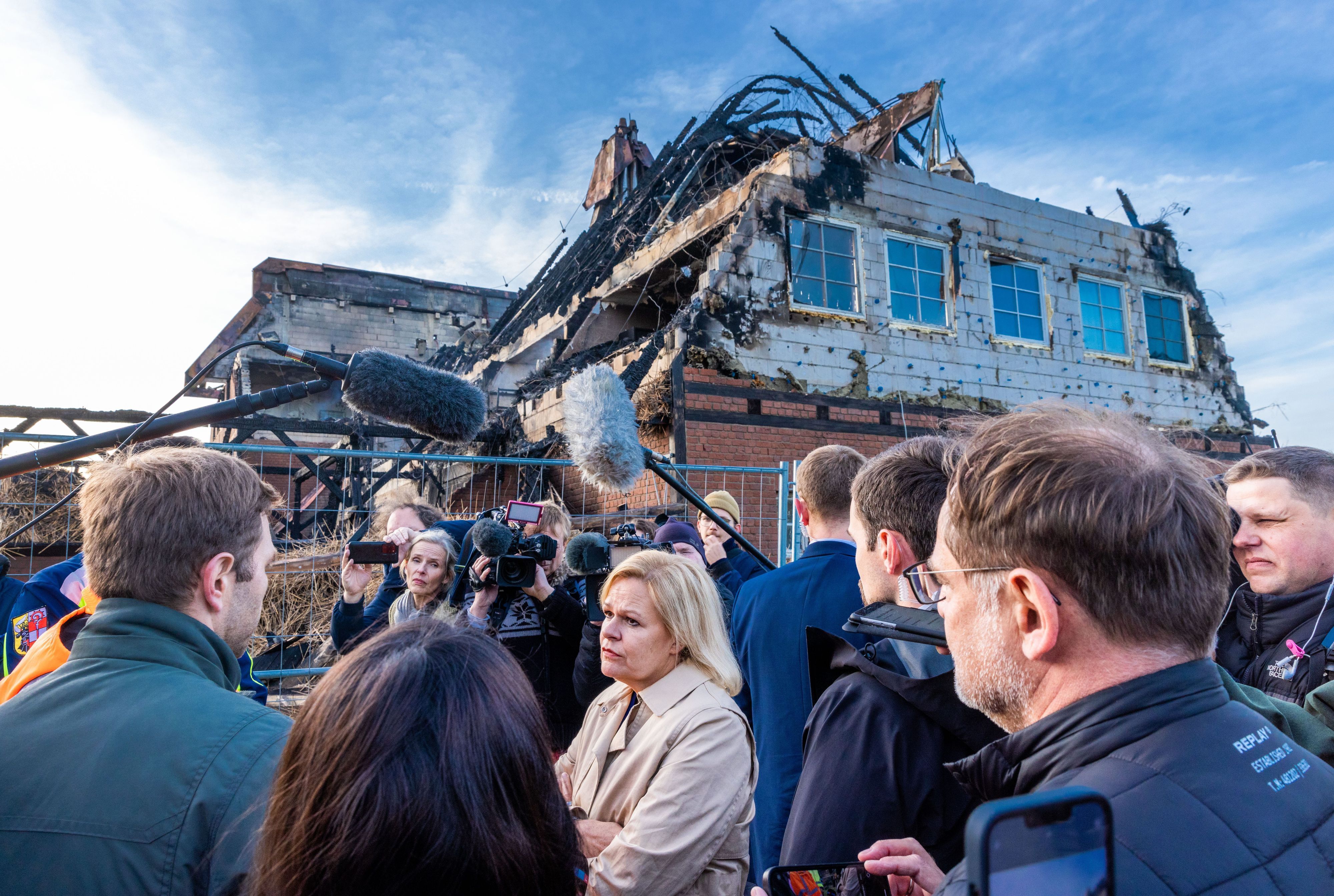 Nancy Faeser (SPD), Bundesinnenministerin, spricht vor einem abgebrannten Hotel mit Andrej Bondartschuk, einem Betreuer der Einrichtung und Augenzeuge des Feuers. Das Gebäude, in dem Geflüchtete aus der Ukraine untergebracht waren, ist abgebrannt.