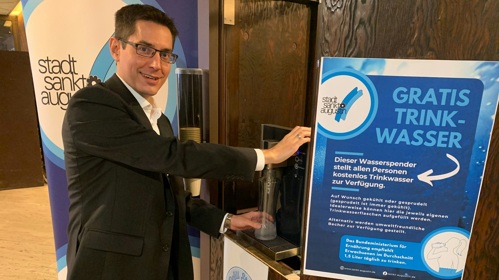 Bürgermeister Max Leitterstorf steht vor einem Wasserspender. Ein Plakat macht auf das kostenlose Wasser aufmerksam.