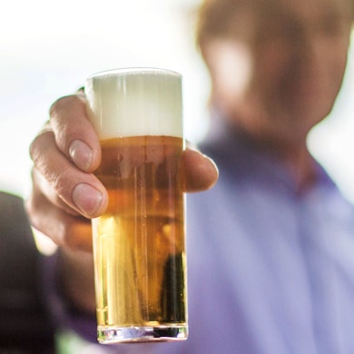 Ein frisch gezapftes Kölsch wird auf einer Party in die Kamera gehalten.