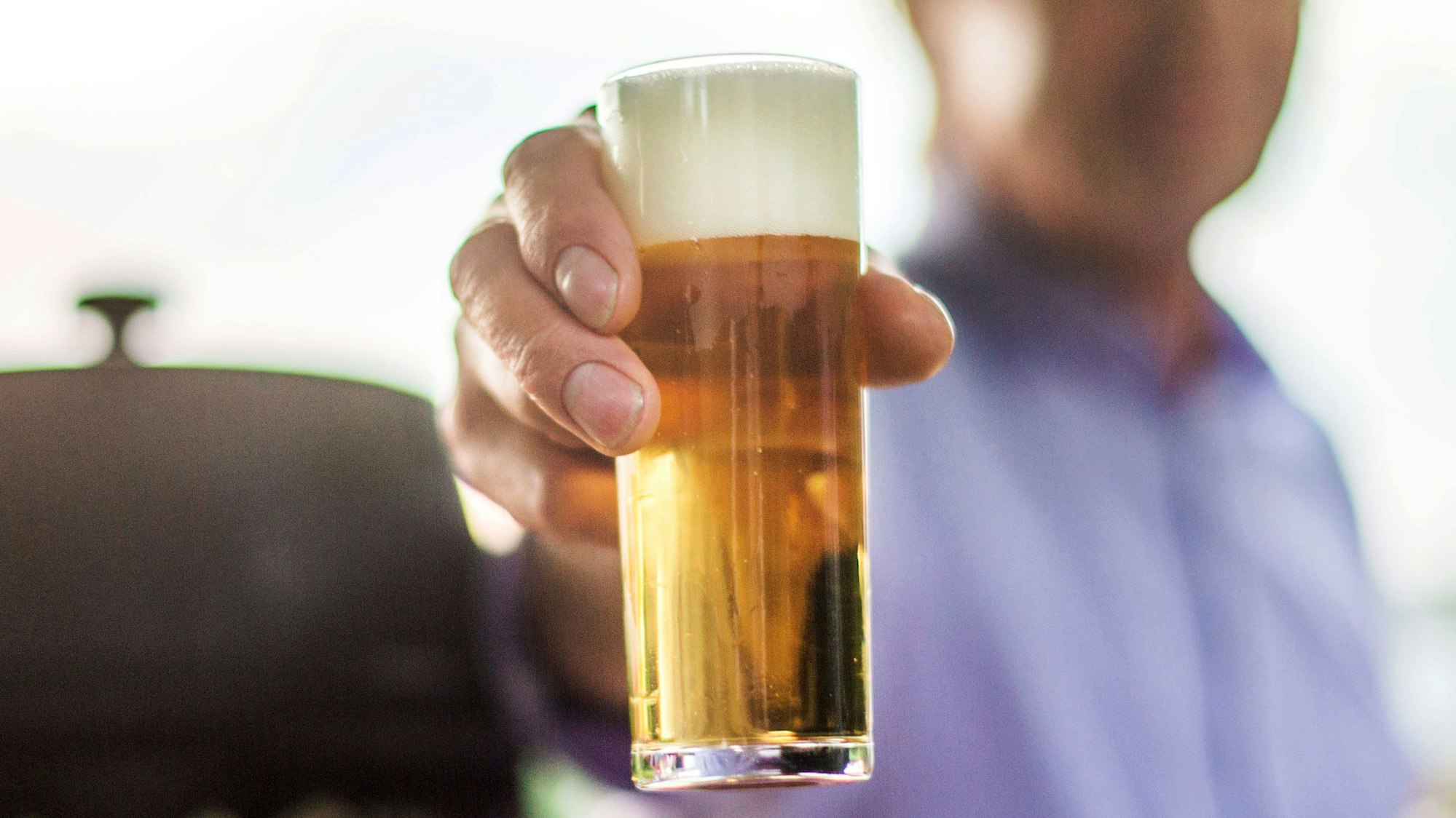 Ein frisch gezapftes Kölsch wird auf einer Party in die Kamera gehalten.