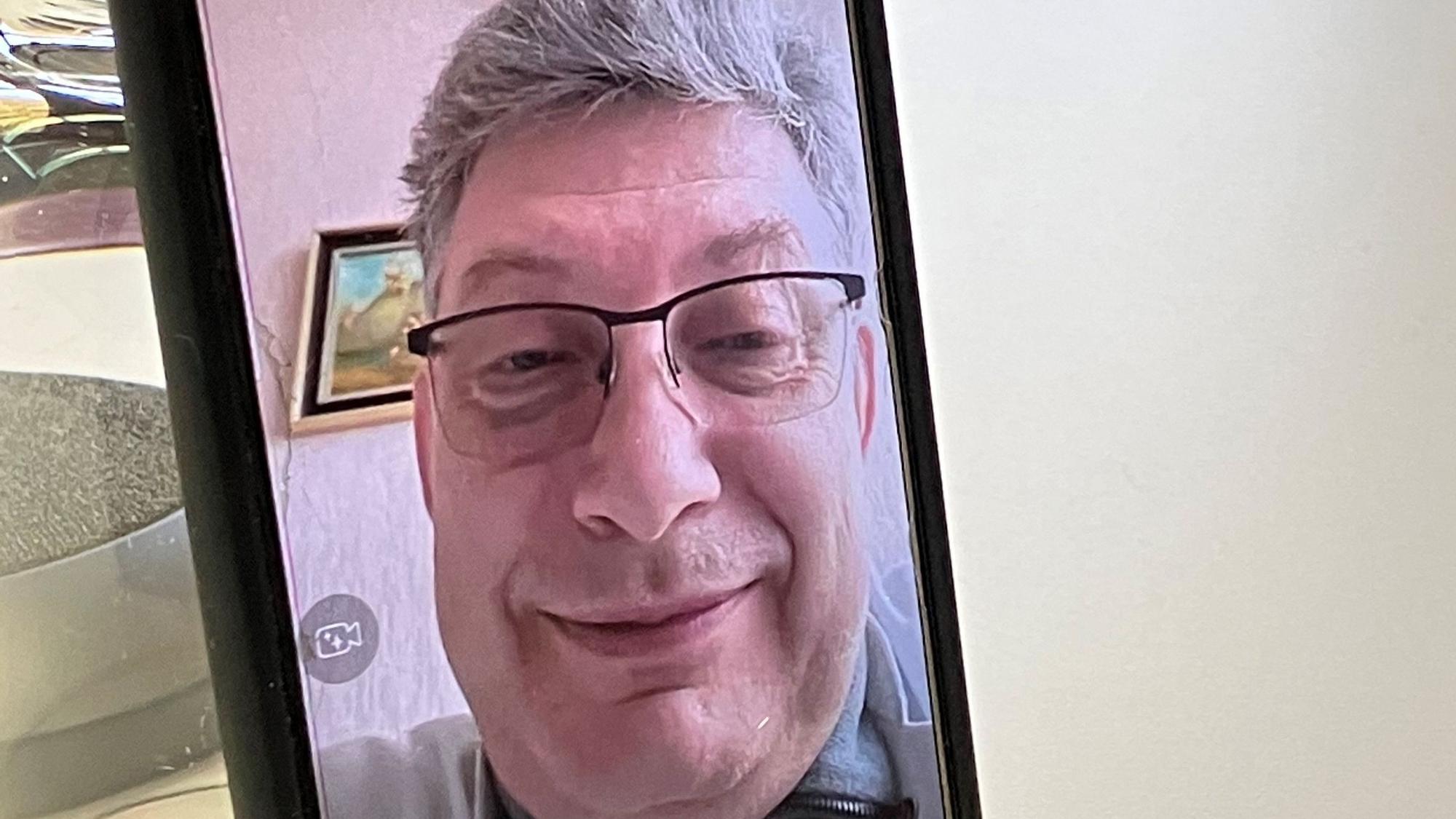 Vitaliy P., Arzt aus Charkiw, ist im Rahmen eines Videotelefonats auf einem Handybildschirm zu sehen.