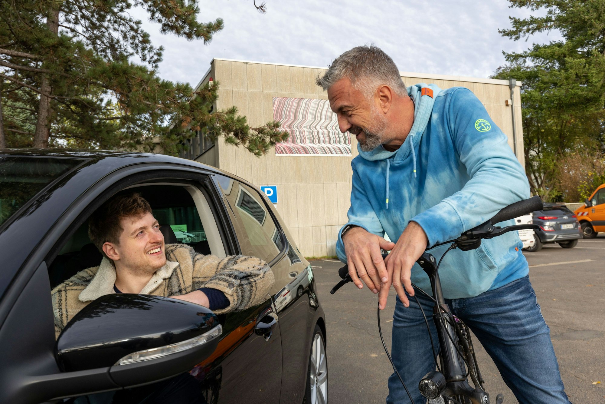 08.11.2022 Swisttal-Ludendorf: Die Berufspendler David Klocke (links in seinem Auto) und Thomas Böttcher (rechts auf seinem Fahrrad) im Gespräch vor dem Swisttaler Rathaus.