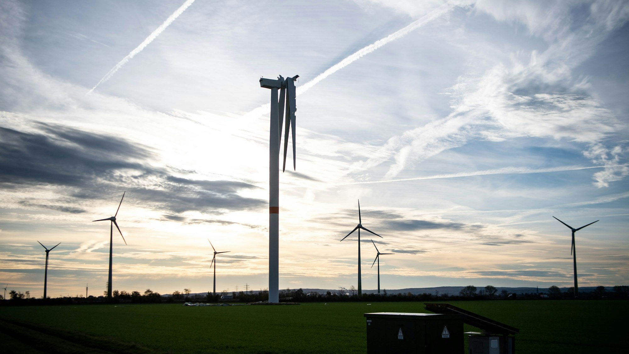 Auf einem Feld bei Zülpich stehen sieben Windräder. Bei dem vordersten fehlt ein Flügel, ein zweiter hängt nur noch in Teilen am Korpus.