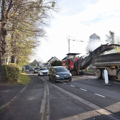 Viele Autos fahren dicht an den Baustellenfahrzeugen auf der B266 vorbei.