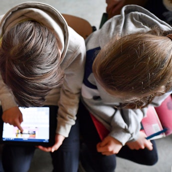 Das Bild zeigt drei Mädchen, die auf ein digitales Endgerät schauen.