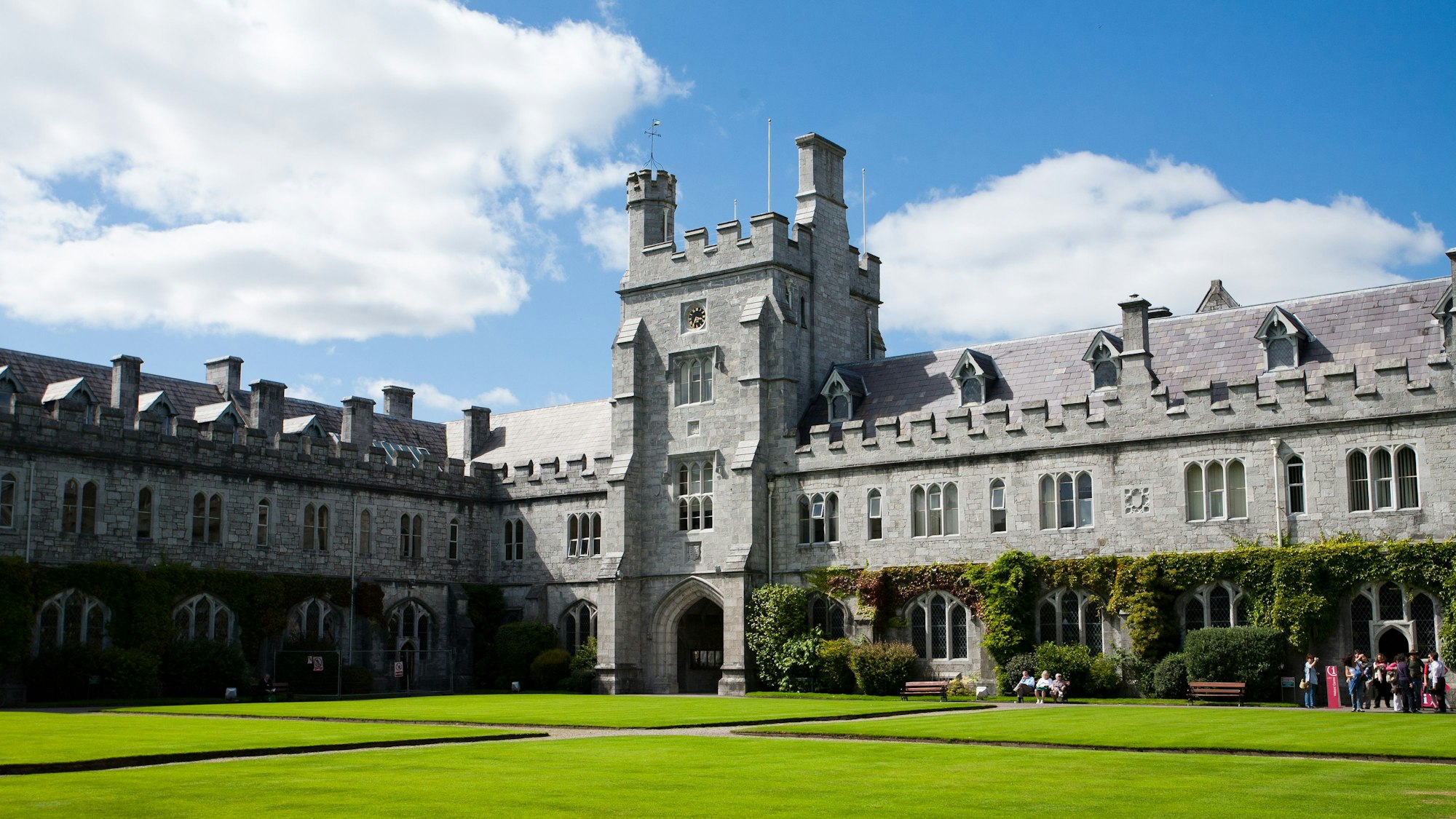 Das irische College ist ein großes altes Gebäude mit Turm in der Mitte. Davor ist eine große grüne Rasenfläche, die sehr gepflegt ist.