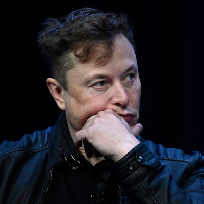 Elon Musk sitzt auf einer Bühne und wird in der Nahaufnahme gezeigt.