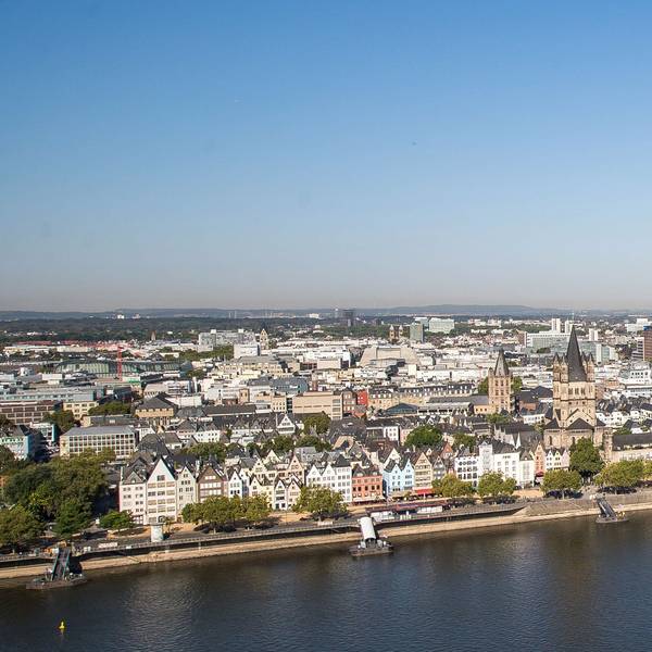 Köln mit Dom, Hohenzollernbrücke, Rhein und Hauptbahnhof bei strahlend blauem Himmel.