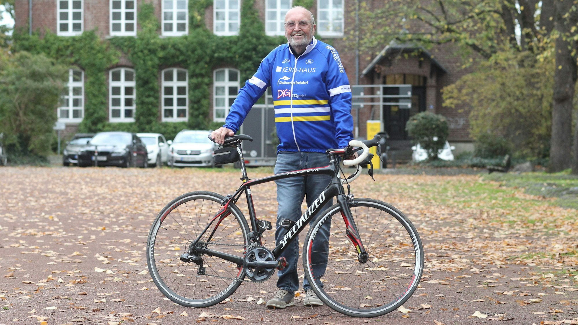 Radsportfunktionär Helmut Elfgen steht mit seinem Rad vor einem Gebäude.