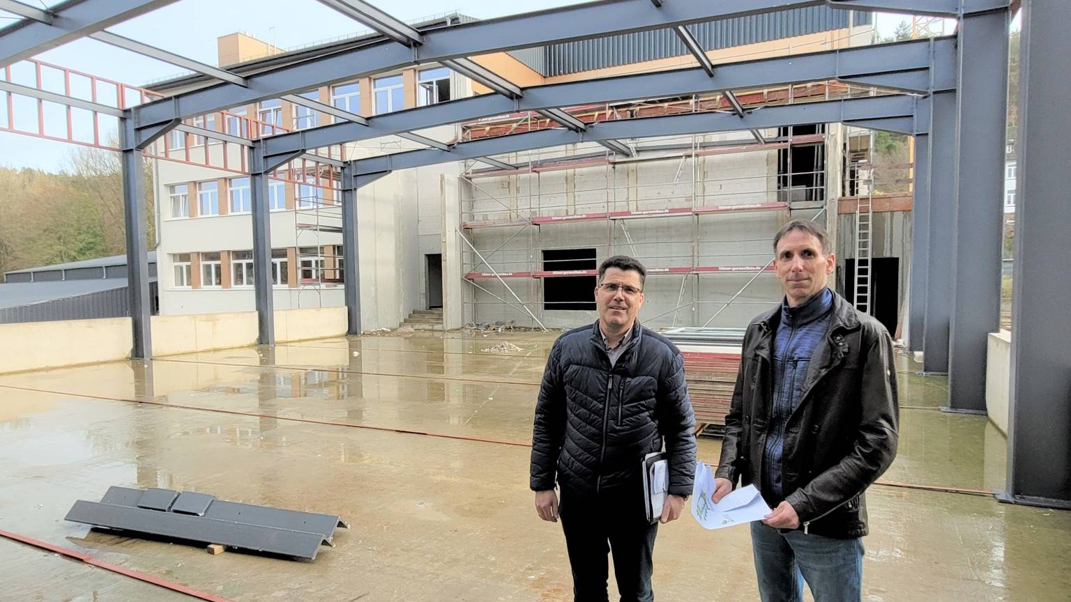 Armin Fischbach und Marcel Wolter stehen im Rohbau der Bürgerhalle im Johannes-Sturmius-Gymnasium Schleiden.