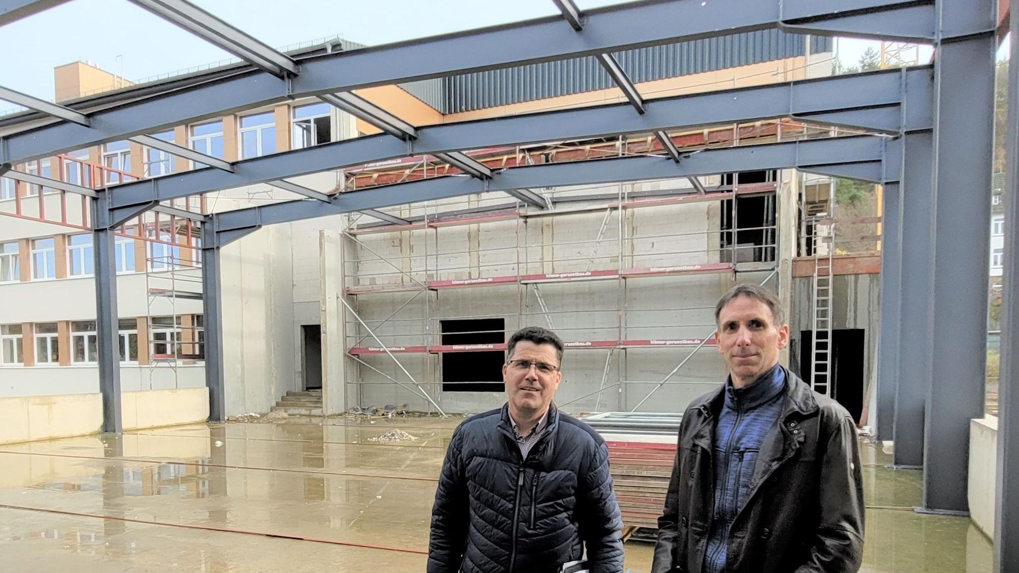 Armin Fischbach und Marcel Wolter stehen im Rohbau der Bürgerhalle im Johannes-Sturmius-Gymnasium Schleiden.