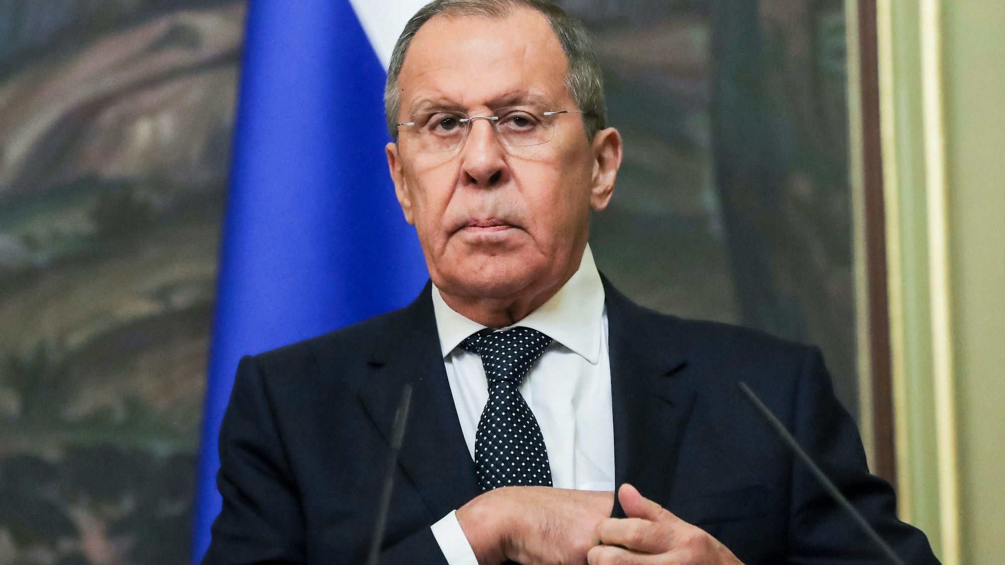 Der russische Außenminister Sergej Lawrow greift sich in die Innentasche des Jacketts und schaut in die Kamera.