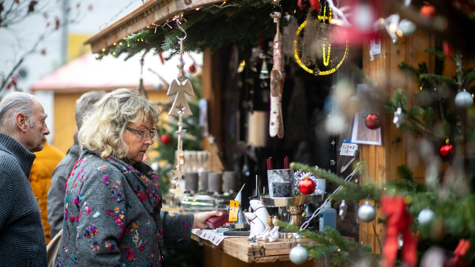 Vor einem Stand für Dekoartikel stehen mehrere Personen und schauen sich das Angebot an.