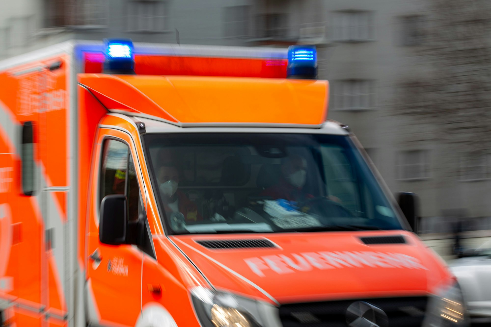 Ein Rettungswagen der Feuerwehr fährt auf einer Straße, das Blaulicht leuchtet.