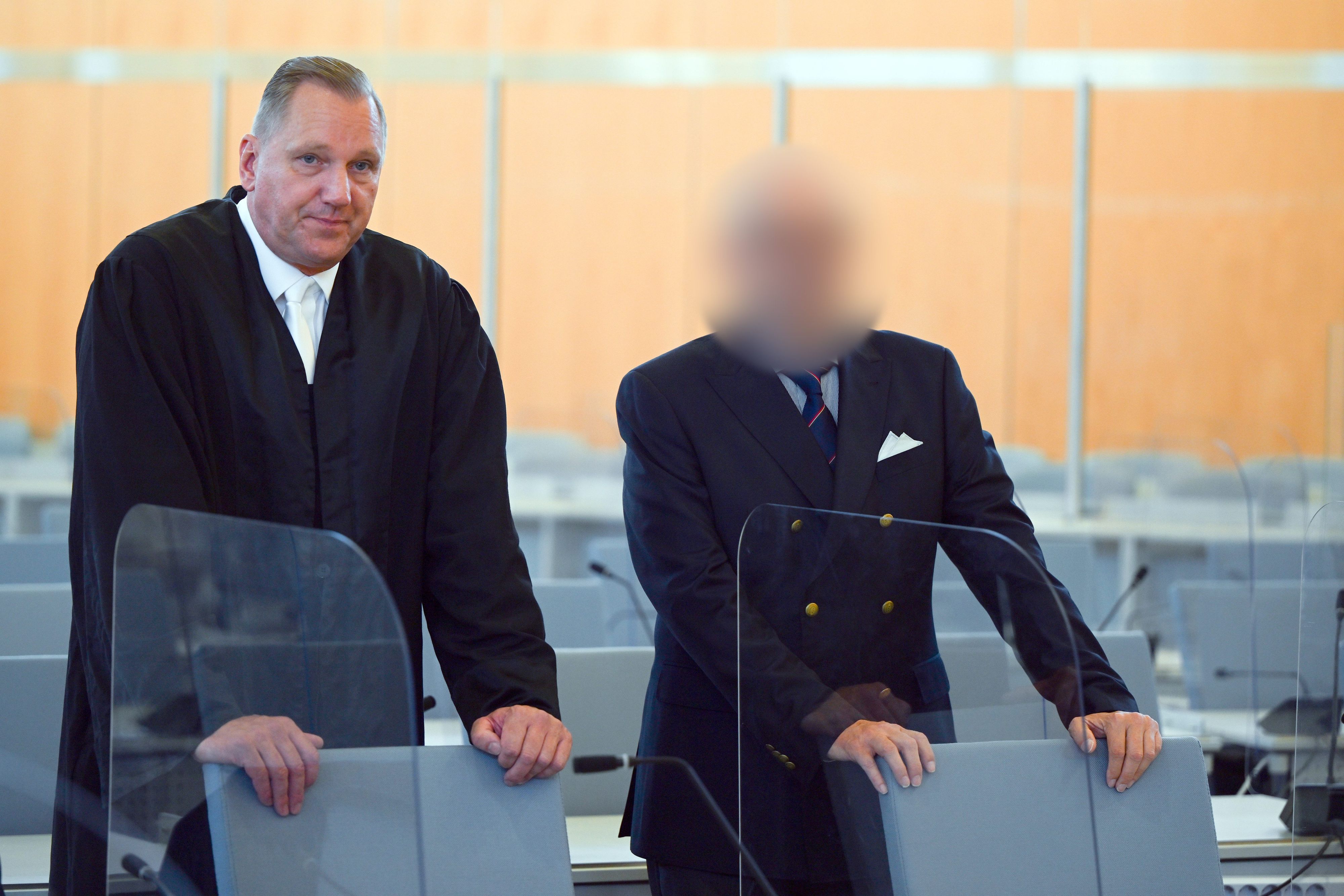 Ein Angeklagter steht mit seinem Verteidiger Christopher Hilgert vor Beginn des Prozesses im Gerichtssaal. Der Angeklagte wurde aus rechtlichen Gründen gepixelt.