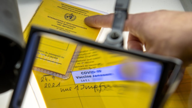 Ein aufgeschlagener Impfausweis mit dem Eintrag einer Corona-Impfung mit dem Impfstoff Johnson & Johnson wird unter einer Lupe betrachtet.