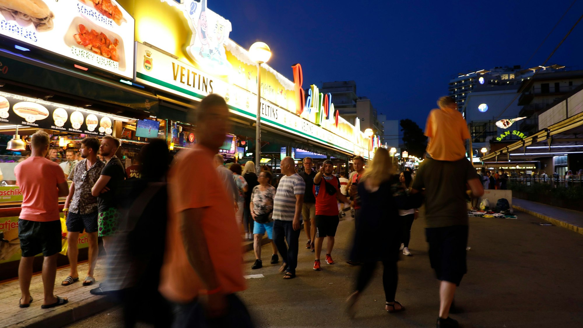 Spanien, Palma: Menschen gehen an der Bar Bamboleo in der Bierstraße am Ballermann vorbei.  Der Sauftourismus um den Ballermann auf Mallorca ist nach Einschätzung von Unternehmern derzeit noch schlimmer als in den Jahren vor der Corona-Pandemie.