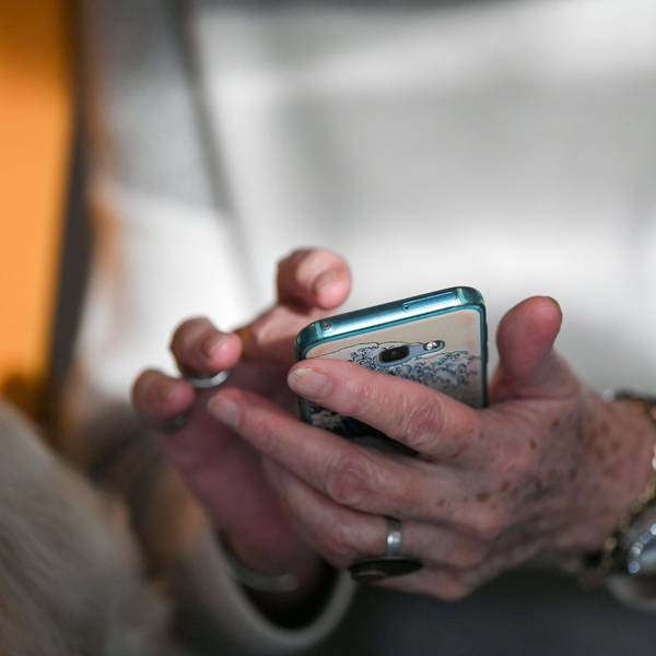 Eine Seniorin hält ein Smartphone in der Hand und tippt auf dem Bildschirm.
