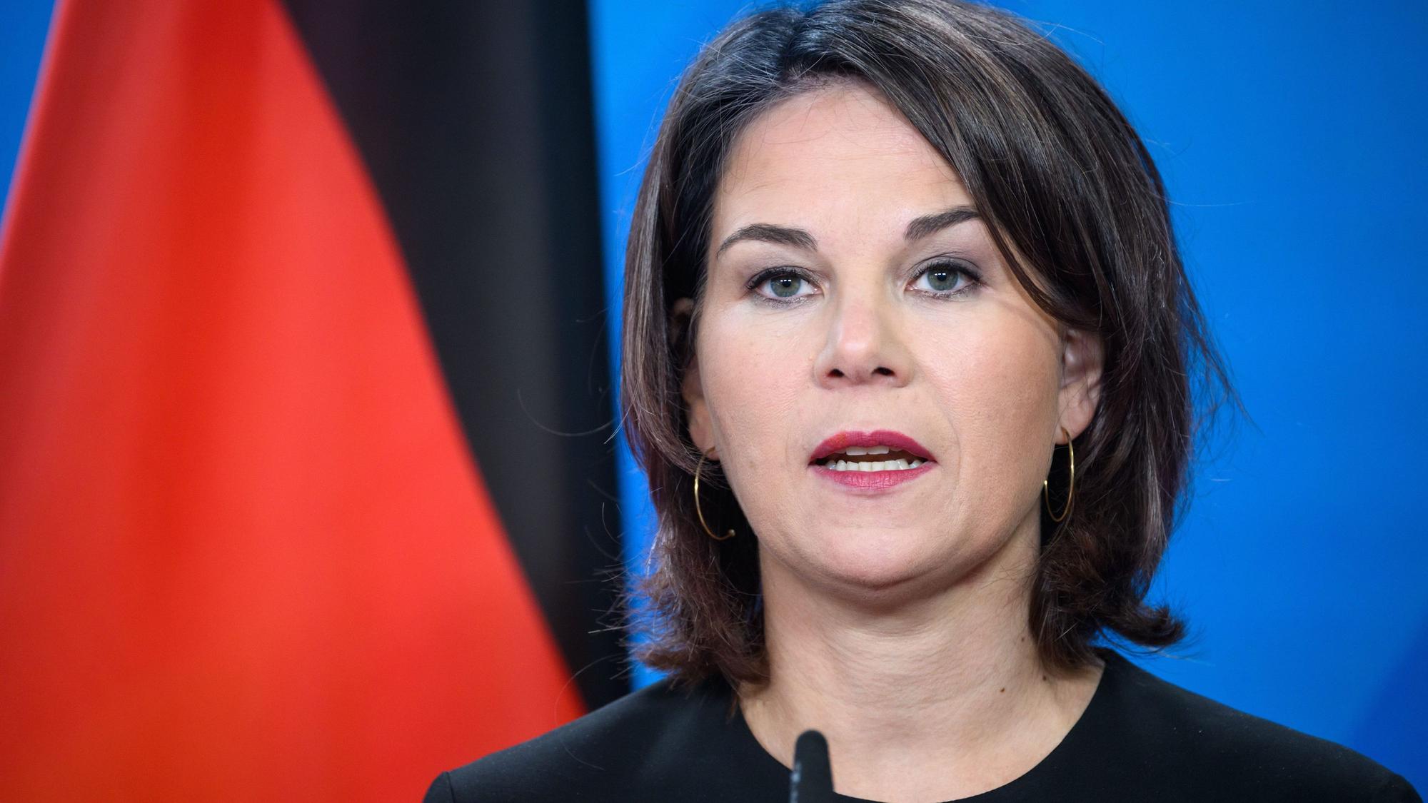 Annalena Baerbock steht bei einer Pressekonferenz am Pult und spricht ins Mikrofon. Im Hintergrund ist eine deutsche Fahne zu sehen.